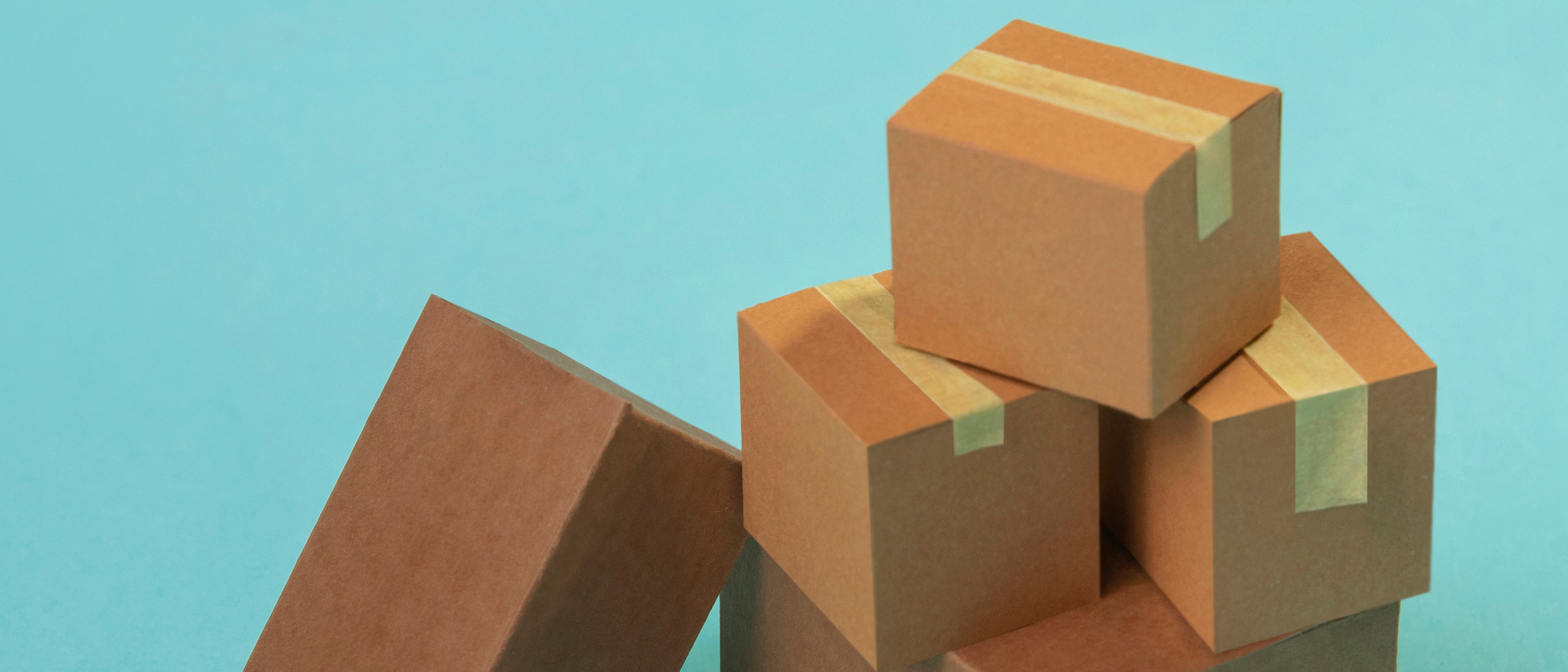 Photograph of several brown cardboard parcels stacked against a turquoise background