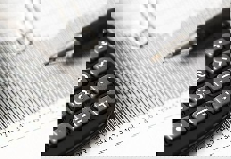 Close up shot of a calculator and a pen on top of a printed chart