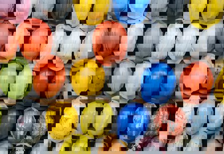 Dozens of different coloured hard hats hung up on a rack