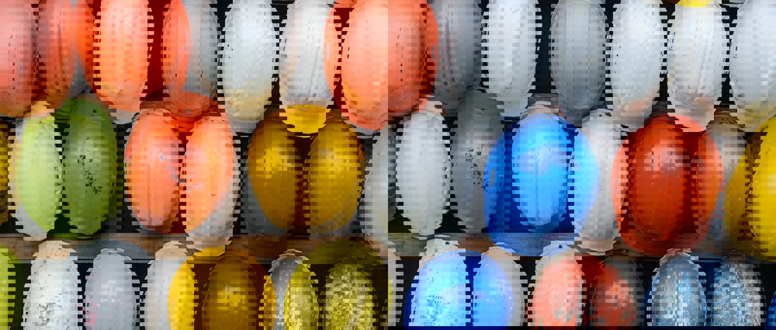 Dozens of different coloured hard hats hung up on a rack