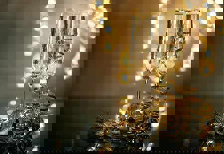 Champagne glasses on a table with festive lights in the background