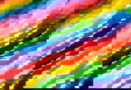 Close up of strands of paint in a rainbow of colours