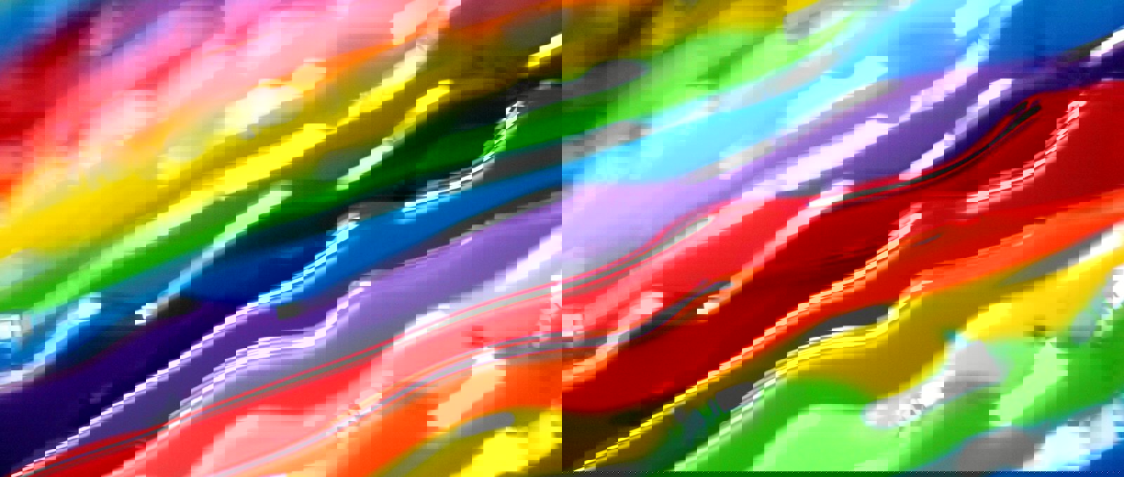 Close up of strands of paint in a rainbow of colours