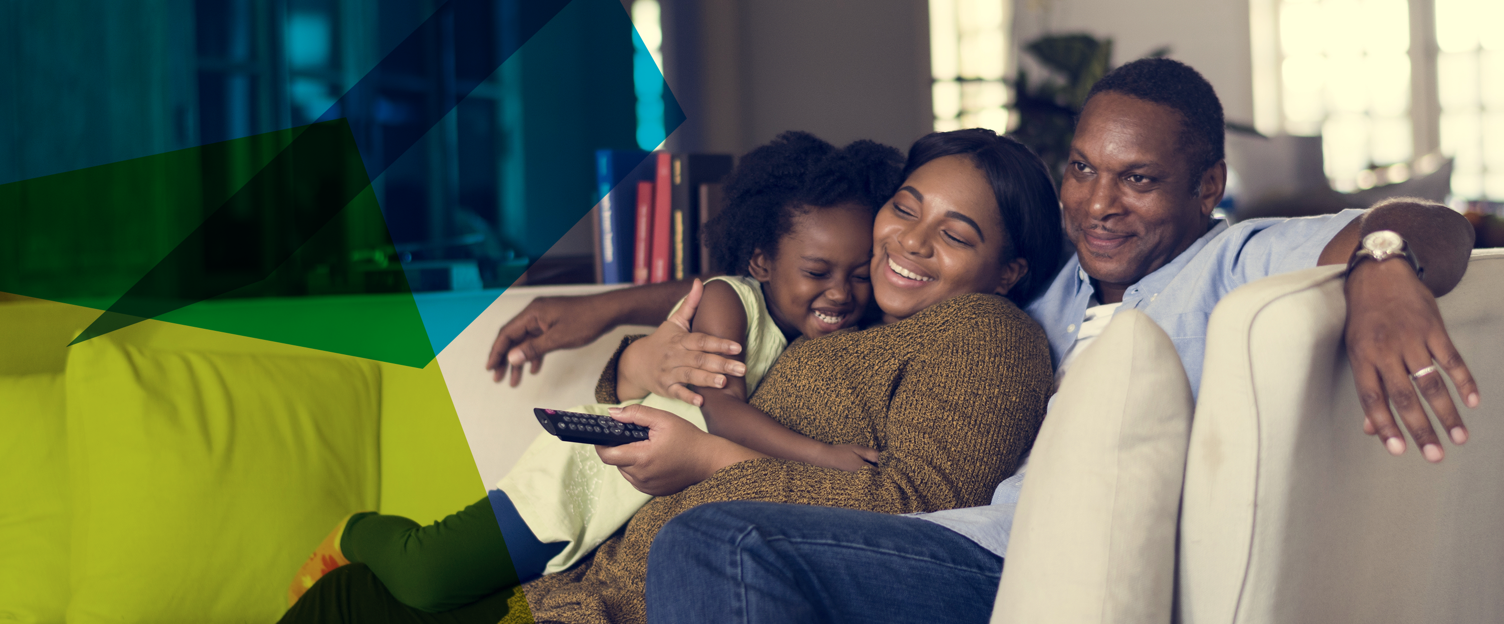Photograph of a family of people of colour on a sofa cuddling and looking happy