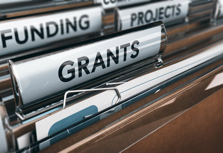 Photograph of tabs above some paper filing folders with words printed on like 'funding' and 'grants'