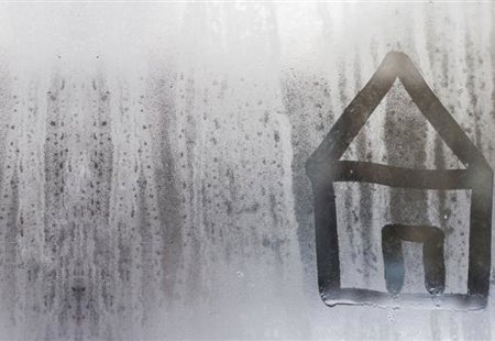 Photograph of condensation on a window. There is a simple image of a house drawn into it. 