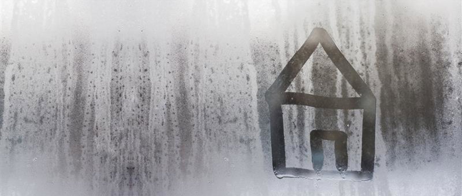 Photograph of condensation on a window. There is a simple image of a house drawn into it. 
