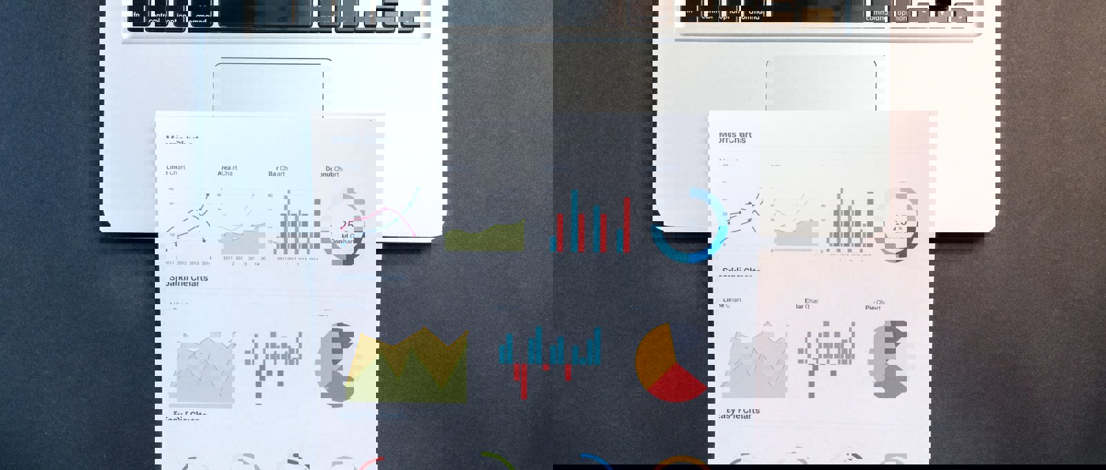 Photograph of a laptop with a printout of various charts lying across the trackpad