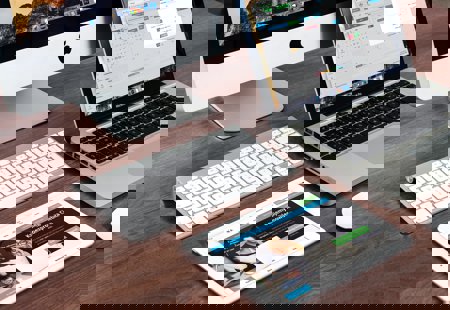 A photo of an imac, macbook and ipad sitting close to each other on a table top