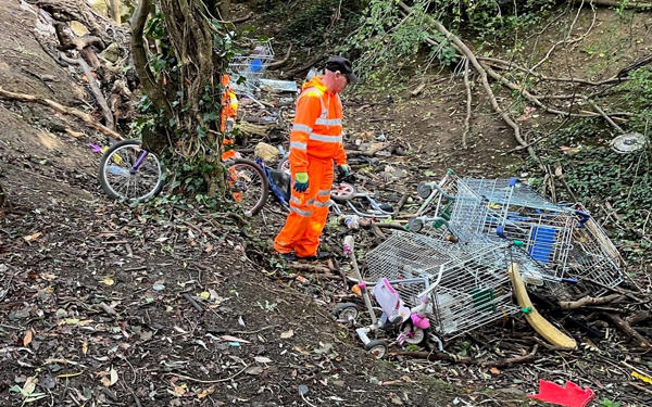 One of our team in orange hi-vis clothing getting ready to clean up some dumped shopping trolleys