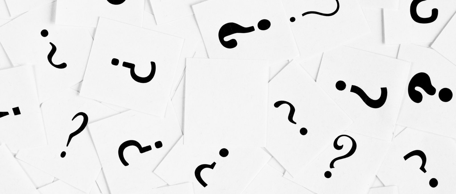 photograph of scattered pieces of paper with questions marks written on them