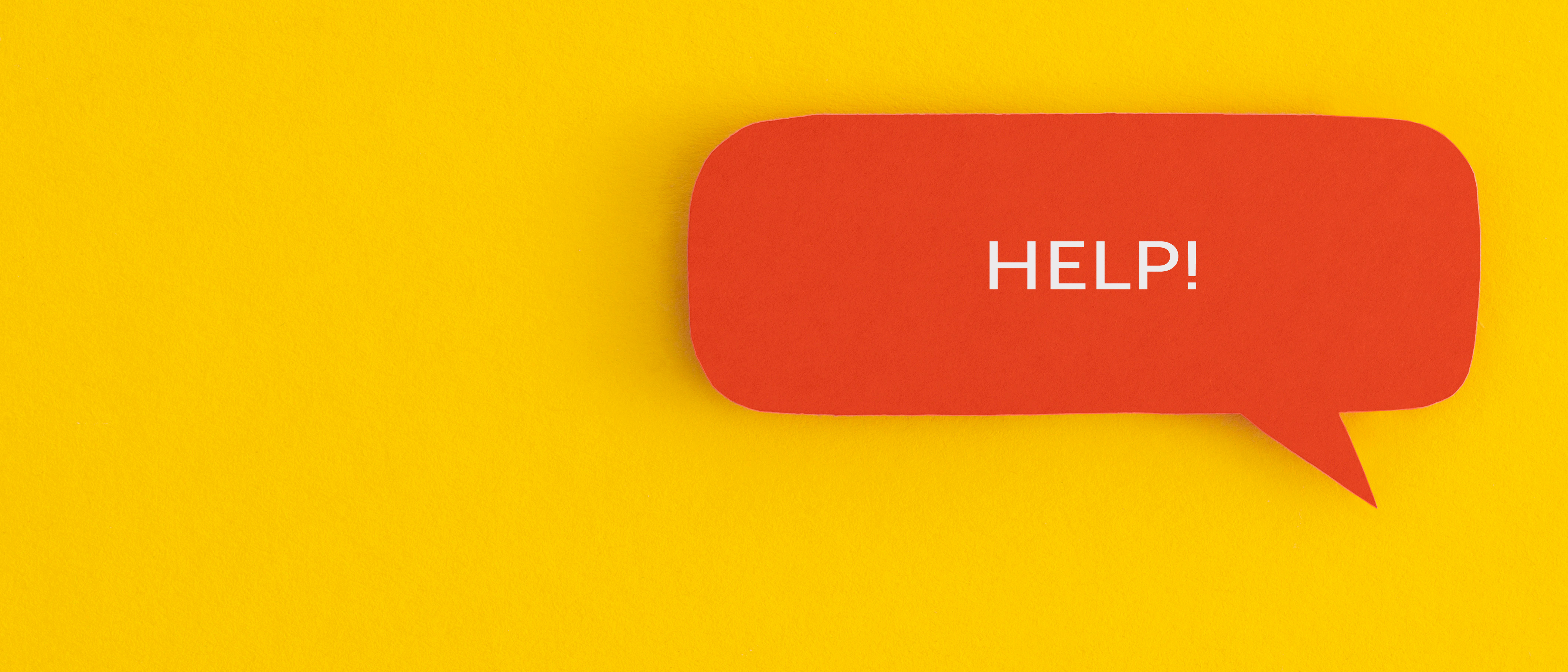 A photo of a red speech bubble against a yellow background' The word 'Help!' is written in upper case in white text inside the speech bubble.