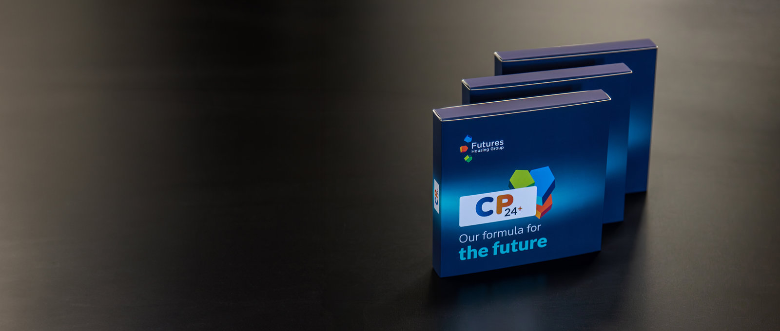 Three corporate plan packs sitting on a dark table