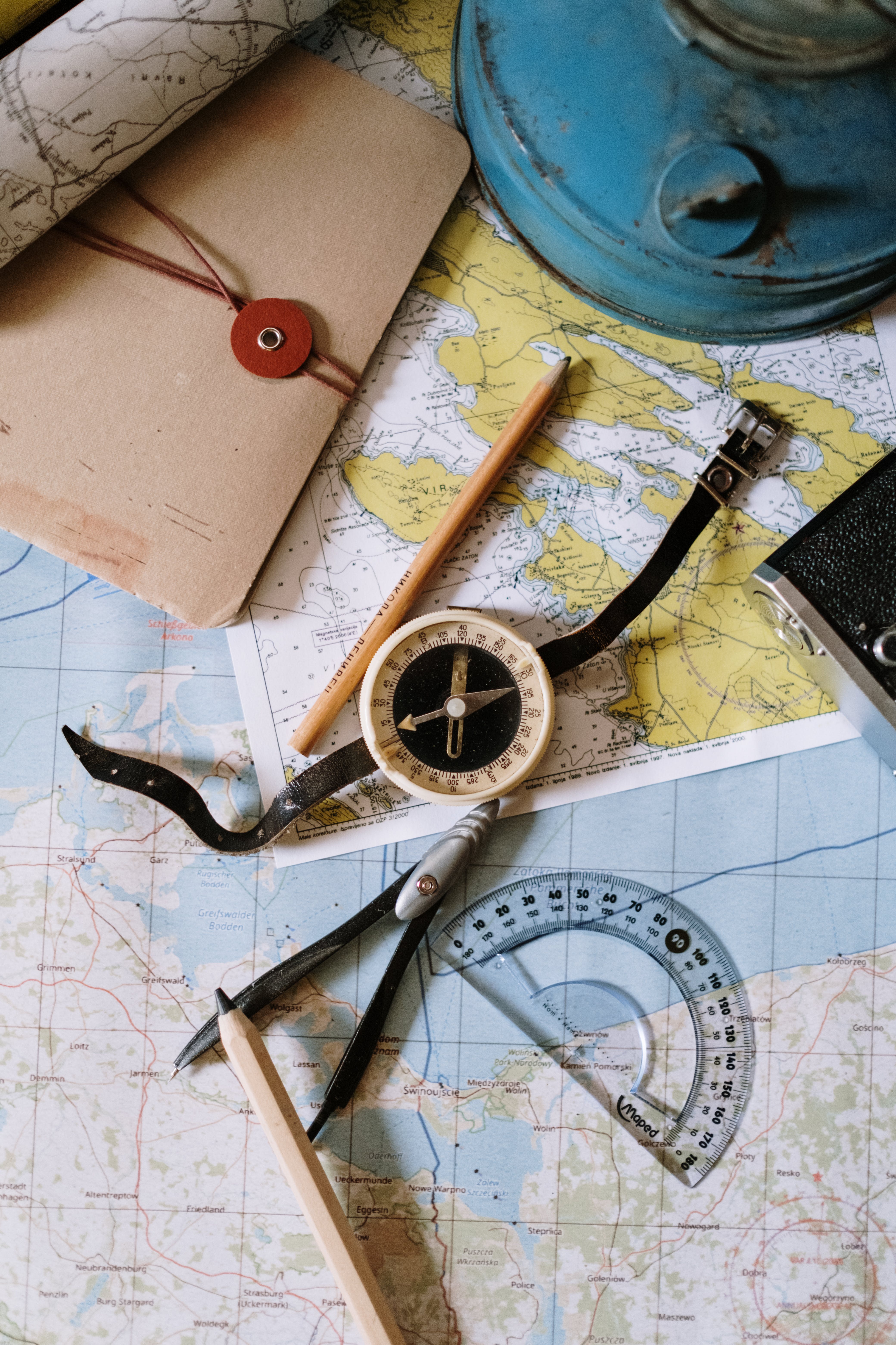 A compass and pencil lying on top of various maps
