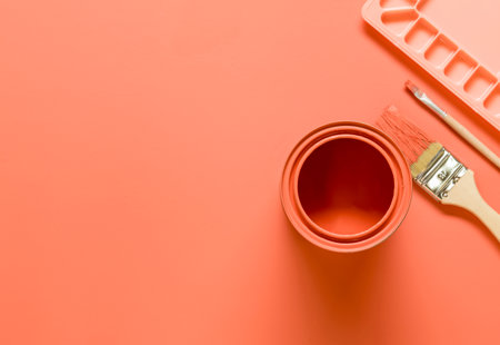 Stylised photo of a paint pot. palette and paint brushes, all pink and lying on a pink surface