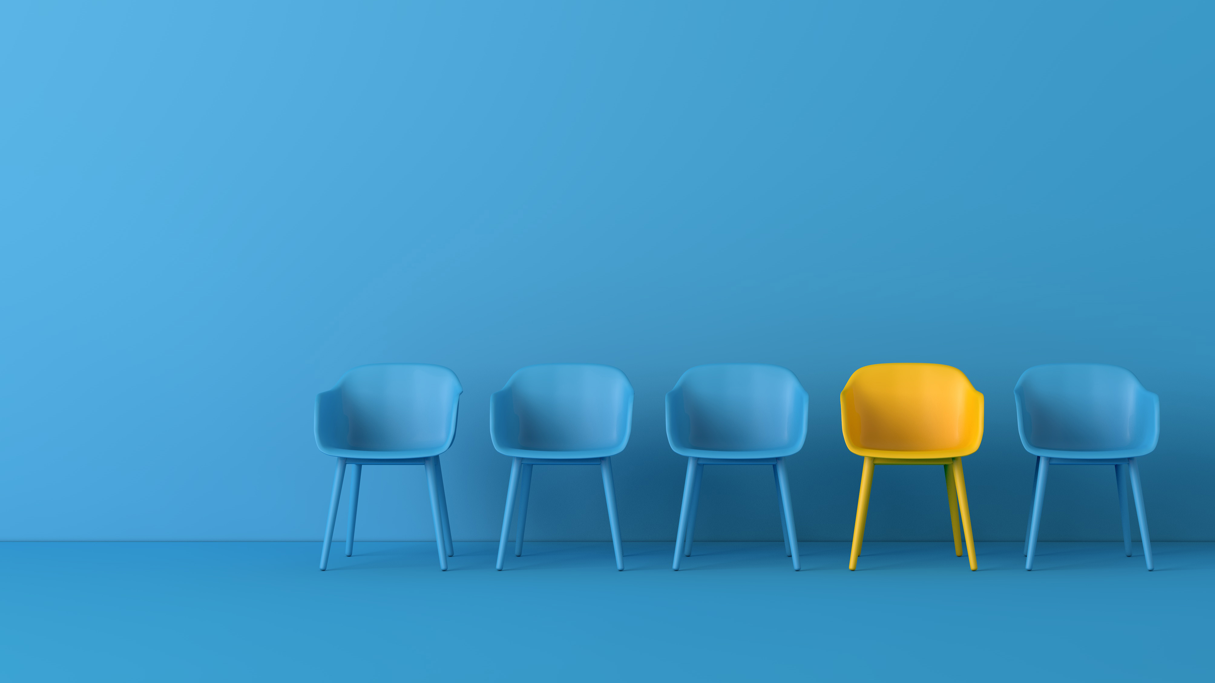 Photo of five chairs against a blue background. All are coloured blue to match the background except one which is bright yellow