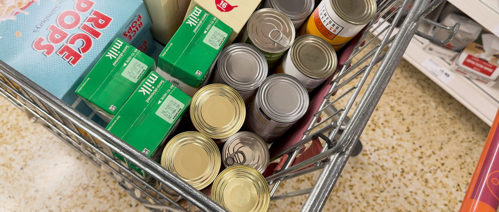 Shopping trolley with tinned items, cartons of milk and cereal