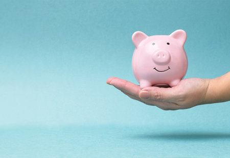 Hand Holding Pink Smiling Piggy Bank, Blue Background
