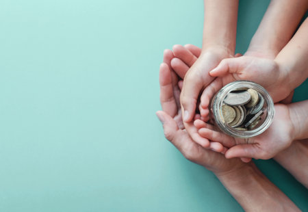 Child and adult hands on top of each other, holding a jar of money on a turquoise background
