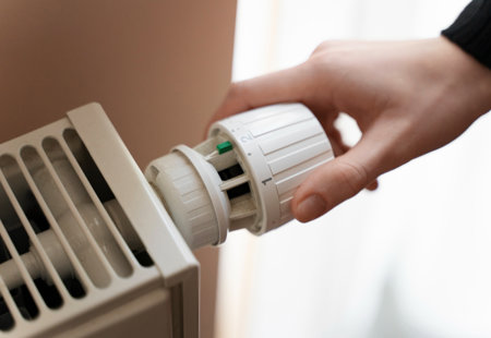 Close-up of a hand turning the heating setting on a radiator