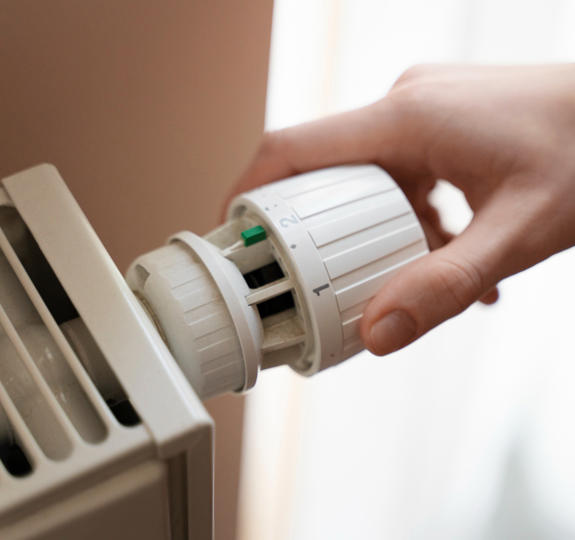 Close-up of a hand turning the heating setting on a radiator