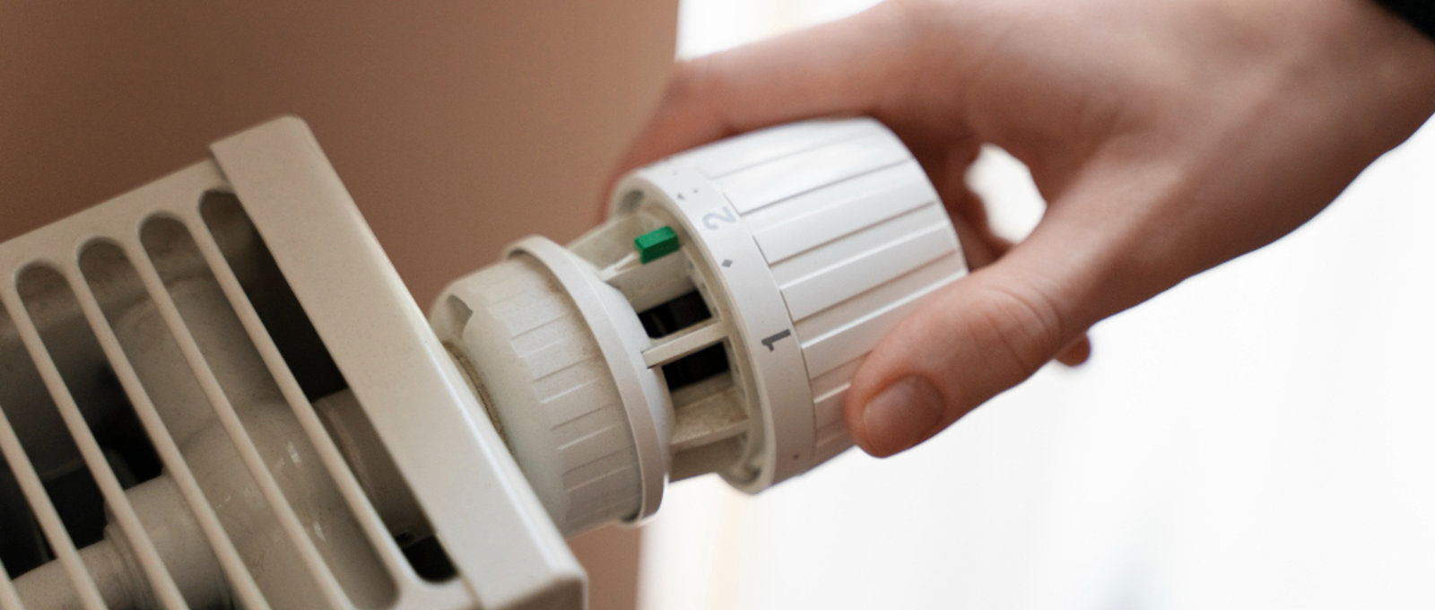 Close-up of a hand turning the heating setting on a radiator